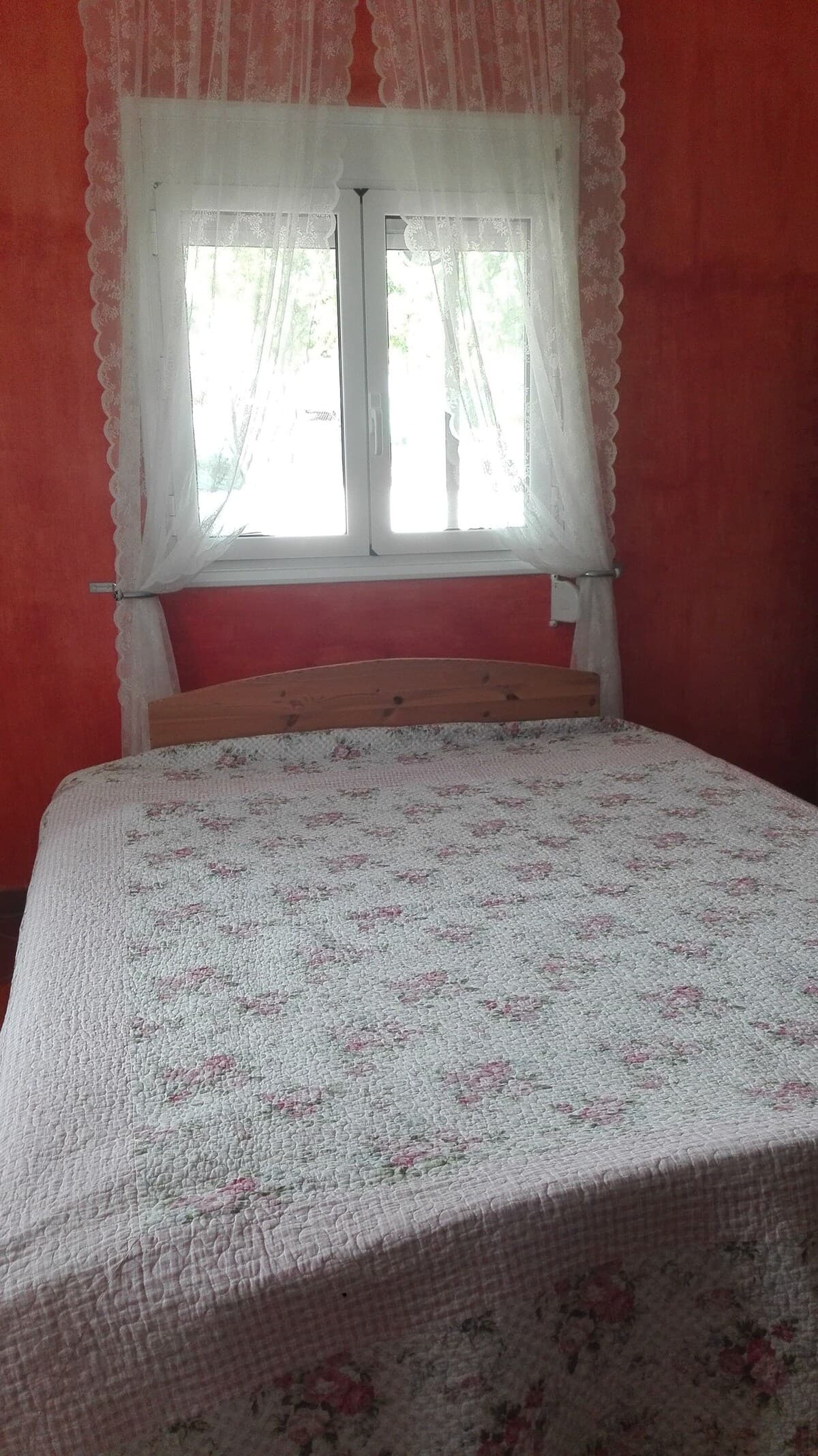 Bedroom with warm terracotta walls and lace curtains